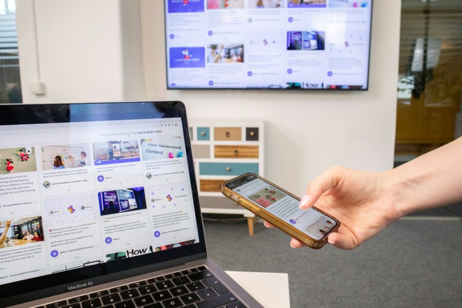 a person holding a cell phone in front of a laptop