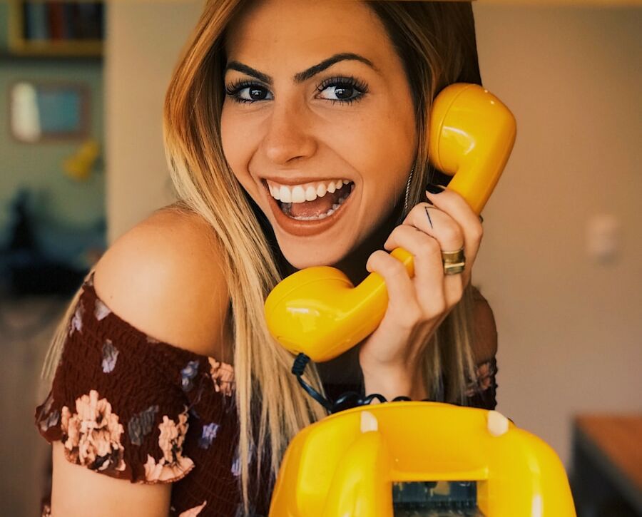 woman holding yellow rotary telephone