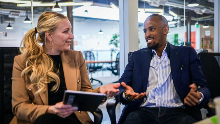 man in black suit jacket sitting beside woman in brown blazer